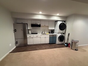 A compact kitchen with built-in appliances, a washing machine, and a trash can. - Cozy 2-bedroom basement in charming Gainesville (Gainesville)