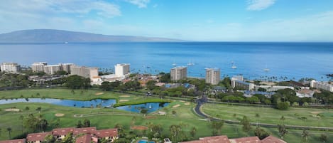 Un resort costero con varios edificios de gran altura, un campo de golf y una extensa masa de agua.