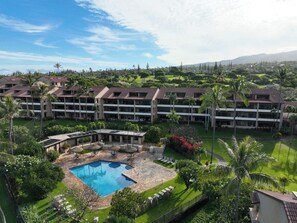 Ein Hotel mit mehreren Etagen, einem Pool und üppiger Bepflanzung.