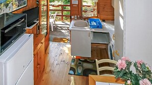 A compact kitchen with a sink, a small refrigerator, and a wooden dining area with a chair and a table. - Gîte semi-mitoyen proche Anduz (Saint-Jean-du-Pin)