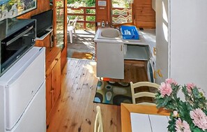 Eine kompakte Küche mit Spüle, kleinem Kühlschrank und einer Holzeinheit mit Tisch und Stuhl.