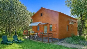 A wooden cabin with a porch, a small deck, and a covered area with chairs. - Gîte semi-mitoyen proche Anduz (Saint-Jean-du-Pin)