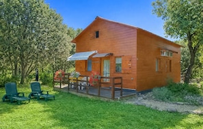 Eine Holzdiele mit Veranda, einer kleinen Terrasse und einem überdachten Bereich mit Stühlen.