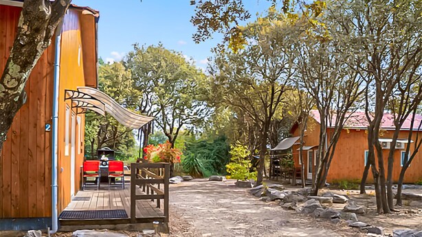 A wooden building with a porch, a covered seating area, and a dirt path. - Gîte semi-mitoyen proche Anduz (Saint-Jean-du-Pin)