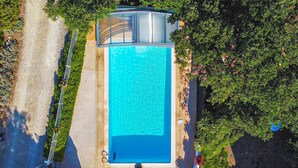 An aerial view of a rectangular swimming pool with a clear blue water surface, surrounded by a concrete deck and lush greenery. - Gîte semi-mitoyen proche Anduz (Saint-Jean-du-Pin)