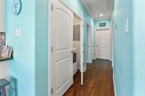 Un couloir aux murs bleu clair, doté d’un plancher en bois et de portes blanches.