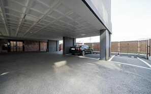 Un espace de stationnement couvert avec une voiture, des piliers en béton et un mur en briques.