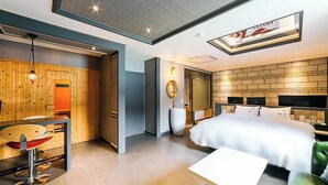 Ein modernes Hotelzimmer mit einem großen Bett, einem Schreibtisch mit Stuhl, einem großen Spiegel und einem an der Wand befestigten Fernseher.