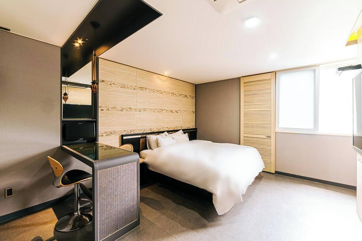 Una habitación de hotel moderna con una cama, un escritorio con una silla, un radiador y una ventana.