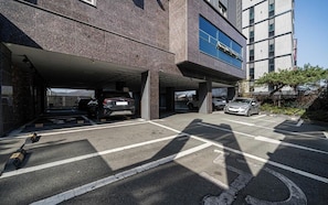 A parking garage with multiple levels, cars parked, and a building with a modern design.