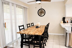 A dining area with a wooden table, black chairs, a wall clock, and a kitchen counter with a coffee machine. - Roomy 3BR & 2BA Retreat with Laundry & King Bed (Hanford)