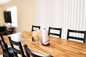 A dining area with a wooden table, black chairs, a vase with flowers, and a white candle.