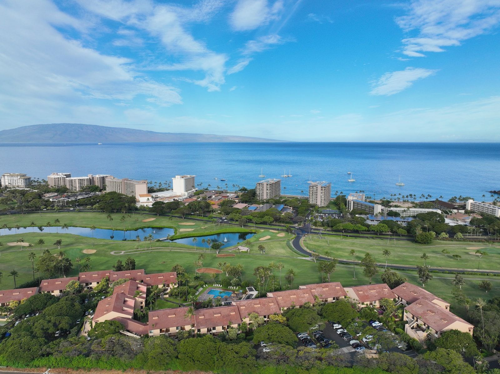 A coastal resort with multiple high-rise buildings, a golf course, and a large body of water.