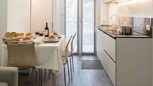 Una cocina moderna con una mesa de comedor para dos, una botella de vino y una cesta de pan.