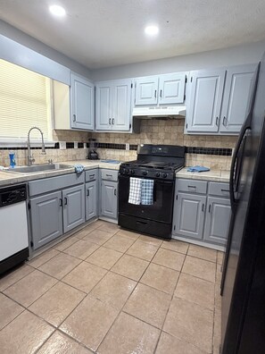 A kitchen with grey cabinets, a black stove, and a dishwasher. - “Stay Awhile ATL/Modern Retreat Near Airport and Downtown Atlanta (Riverdale)