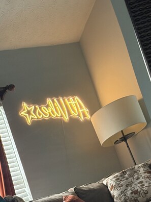 A room with a neon sign, a lamp, and a patterned cushion. - “Stay Awhile ATL/Modern Retreat Near Airport and Downtown Atlanta (Riverdale)