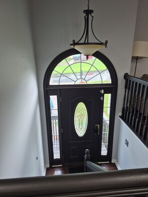 A staircase leading to a door with a stained glass window, a black railing, and a view of the street outside. - “Stay Awhile ATL/Modern Retreat Near Airport and Downtown Atlanta (Riverdale)