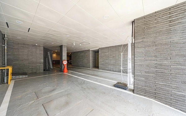 A spacious indoor area with a high ceiling, grey brick walls, and a polished concrete floor.