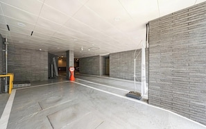 Un vaste espace intérieur doté d’un haut plafond, de murs en briques grises et d’un sol en béton poli.