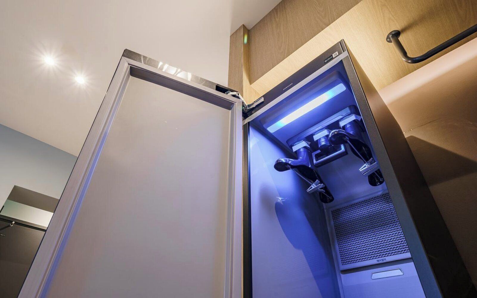 Un refrigerador abierto con luz azul, un asa y un panel de control.