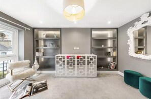 Ein modernes Wohnzimmer mit einem weißen Sofa, einem dekorativen weißen Schrank und einem großen Spiegel.