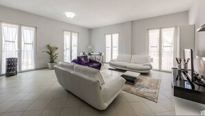 A spacious living room with a white sofa, a purple armchair, a coffee table, and a TV stand. - Central G Juhadol 2BR Apartment With Free Parking (Shkodër)
