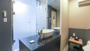 A modern bathroom with a large sink, a mirror, and a small table with toiletries. - Gamdong Hotel (Busan)