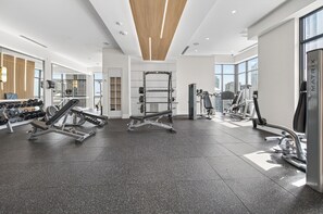 Ein modernes Fitnessstudio mit unterschiedlichen Trainingsgeräten, großen Fenstern und einem aufgeräumten, großzügigen Raum.