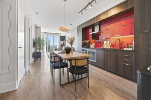 Eine moderne Küche mit dunklen Holzschränken, einer roten Rückwand und einem Essbereich mit Holztisch und -stühlen.