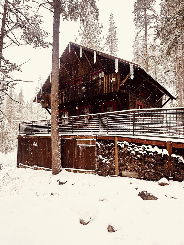 Eine Holzhütte mit Balkon, umgeben von schneebedeckten Bäumen.