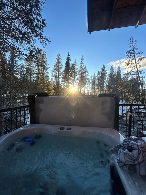 Un jacuzzi con vistas a un bosque y al atardecer.