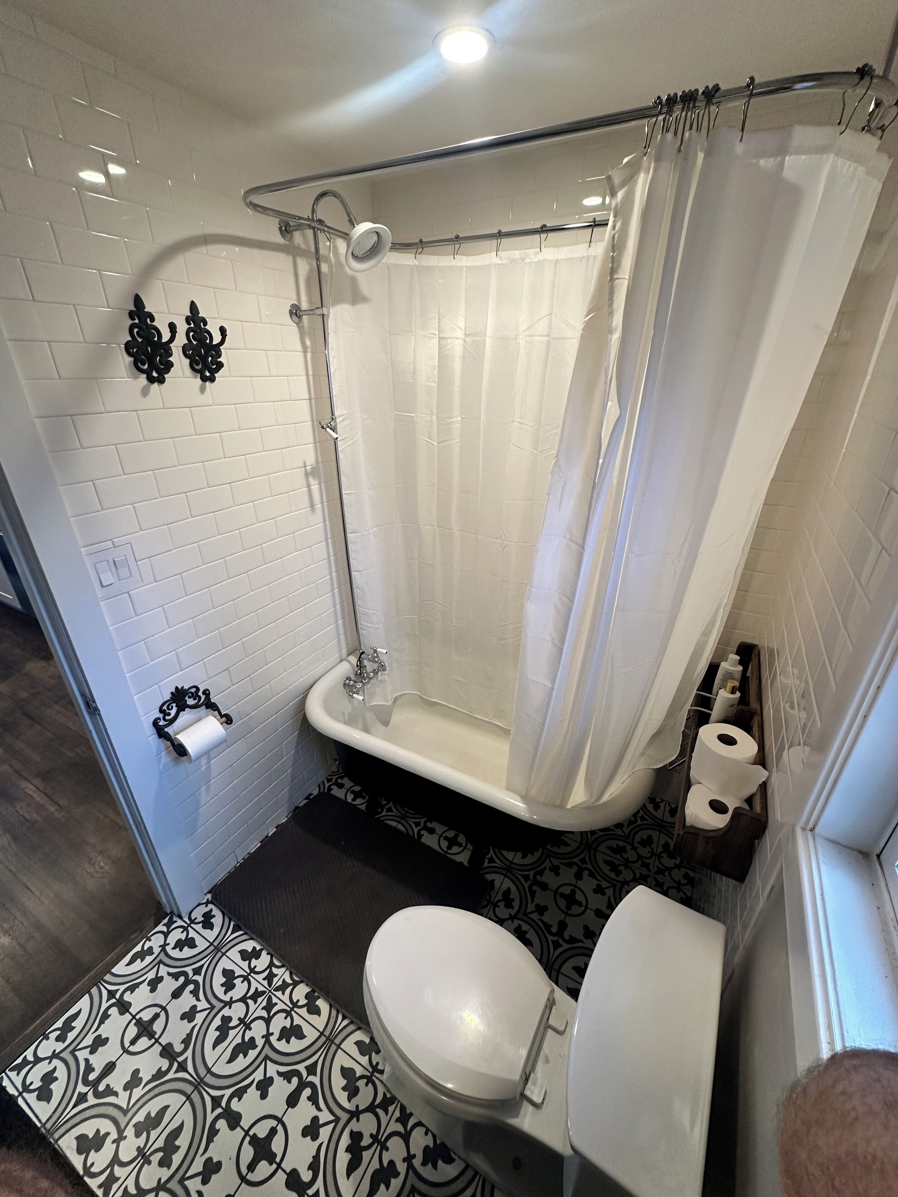 A bathroom with a bathtub, toilet, and patterned floor.