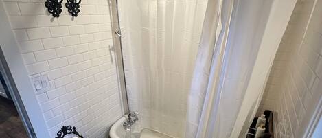 A bathroom with a bathtub, toilet, and patterned floor.