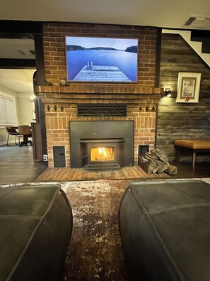 Una chimenea con un televisor encima, un banco y una pila de leña.