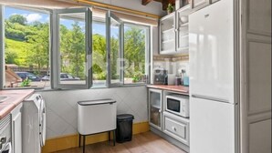 A kitchen with a large window, wooden ceiling beams, and white cabinetry. - La Casina de Pepa - country house in Roiz, birthplace of Juan de Herrera (Roiz)