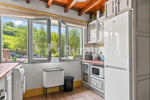 Eine Küche mit großem Fenster, Holzbalkendecke und weißen Schränken.