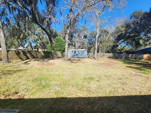 A backyard with a shed, trees, and a wooden fence.