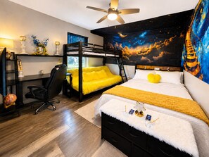 Una camera da letto con un letto a castello, una scrivania, una sedia e una ventola a soffitto.