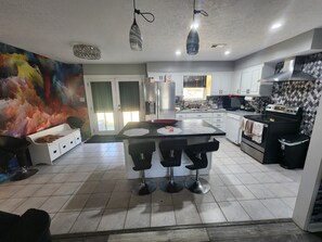 Una cucina moderna con isola centrale, sgabelli da bar, frigorifero e forno a microonde.