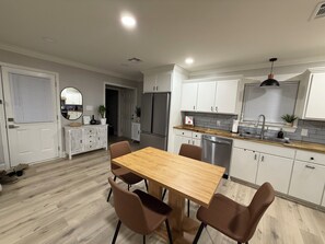 Eine moderne Küche mit weißen Schränken, einem Holztisch und einem Edelstahl-Kühlschrank.