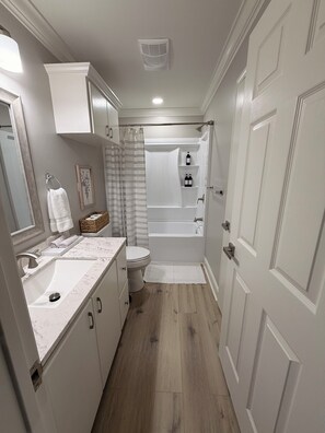 Ein Badezimmer mit weißem Waschbecken, Toilette, Badewanne und Duschvorhang.
