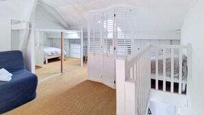 Una habitación con literas, un escritorio, una silla y un espejo grande.