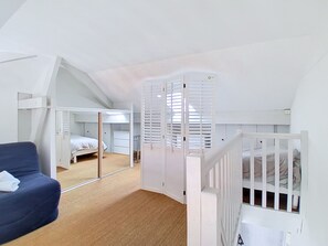Ein Zimmer mit Etagenbett, Schreibtisch, Stuhl und einem großen Spiegel.