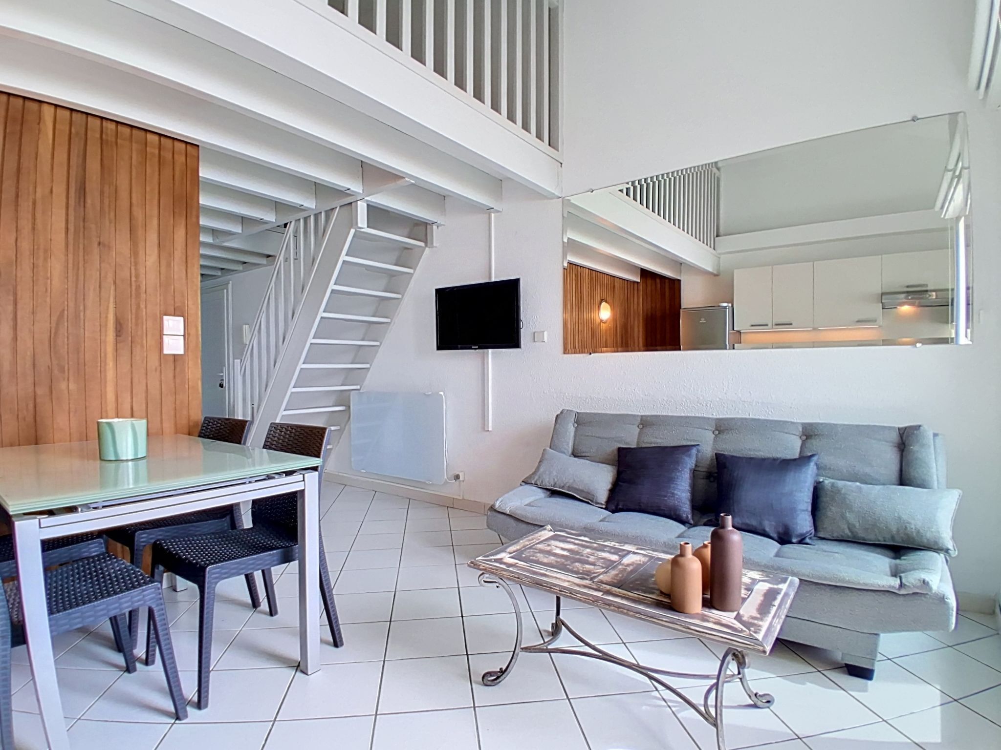 A modern living room with a sofa, coffee table, and dining area.