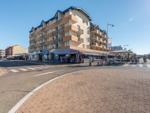 Ein mehrgeschossiges Hotel mit Balkonen, einer Straße davor und Außenbestuhlung für Cafés.