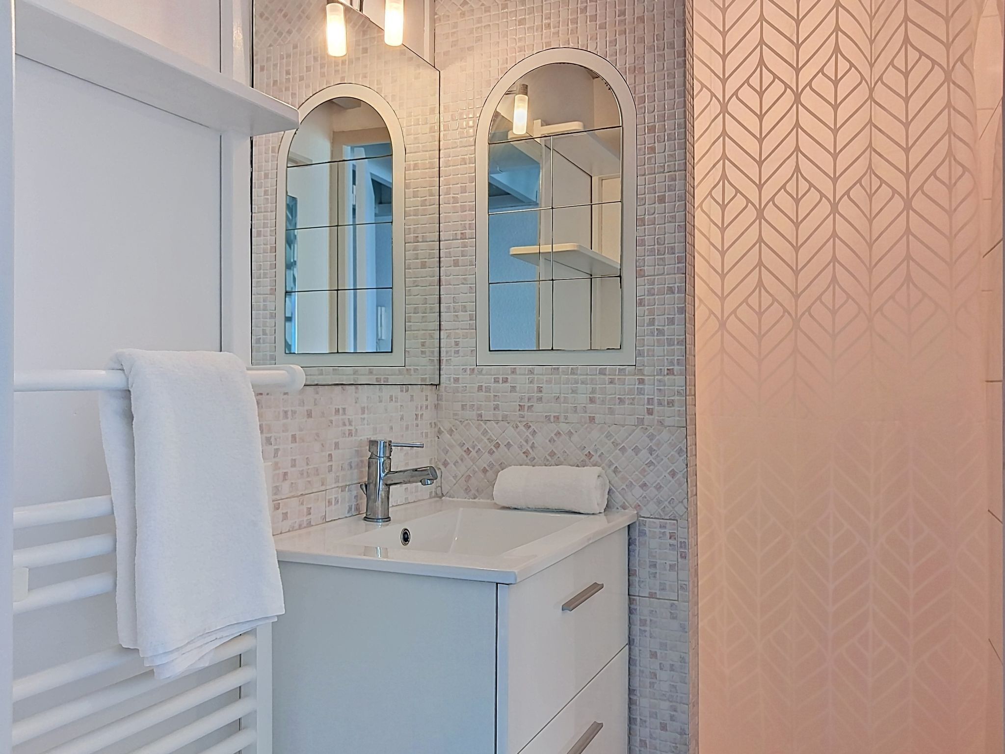 A bathroom with a white vanity, a mirror, and a tiled backsplash.