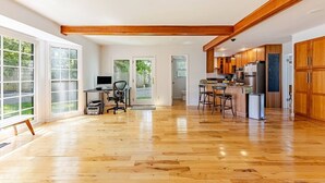 Une cuisine spacieuse avec des meubles en bois, un coin repas doté de tabourets de bar et un espace aménagé pour un bureau à domicile.