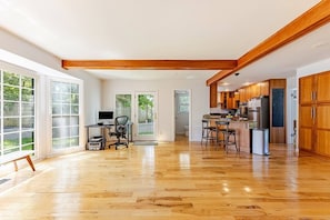 Eine geräumige Küche mit Holzausstattung, ein Essbereich mit Barhocker und ein Home-Office-Arbeitsplatz.