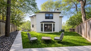 Une maison à deux étages dotée d’un patio comprenant deux chaises et une table.