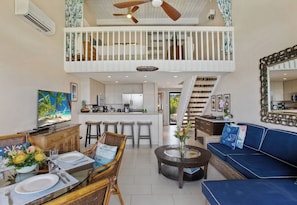 A spacious living area with a high ceiling, a dining set, a sofa, a coffee table, and a kitchen in the background. - Napili Point 3 Waterfront Villas, Sleeps 16 | Car Incl. w/ 6 nights | ML-4083 by KBM (Lahaina)